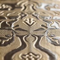 Macro di una complessa trama di tessuto jacquard damascato, con motivi intricati e lucenti.