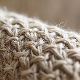 Macro di una trama di tessuto in lino naturale grezzo, mostrando le fibre robuste e organiche.